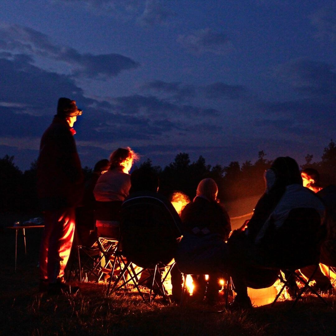 personas en circulo frente a fogata en campamento
