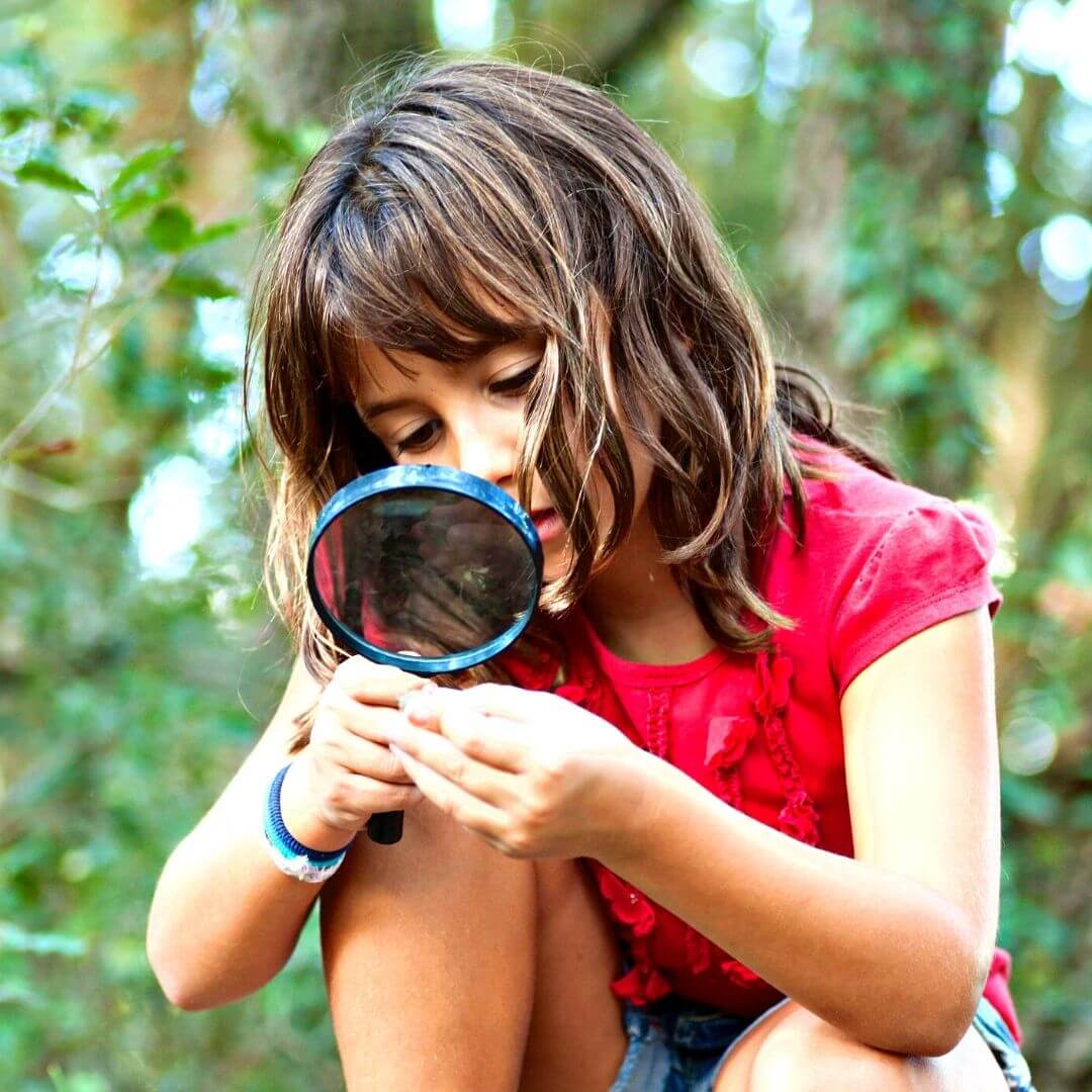 niña observando plantas con una lupa